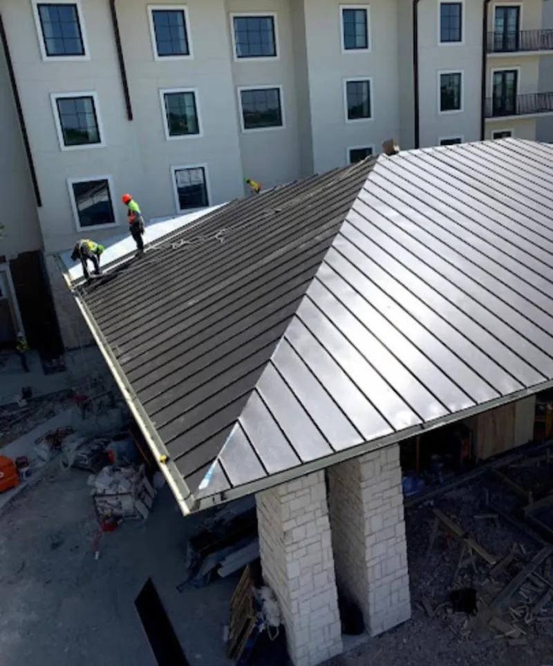 Crew installing standing seam metal roof panels on a commercial project in Brownfields